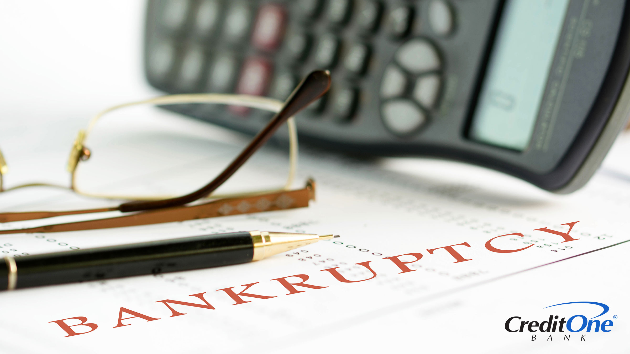 A page titled Bankruptcy sits on a desk beside a calculator, glasses and pen, ready to create a plan to rebuild credit.