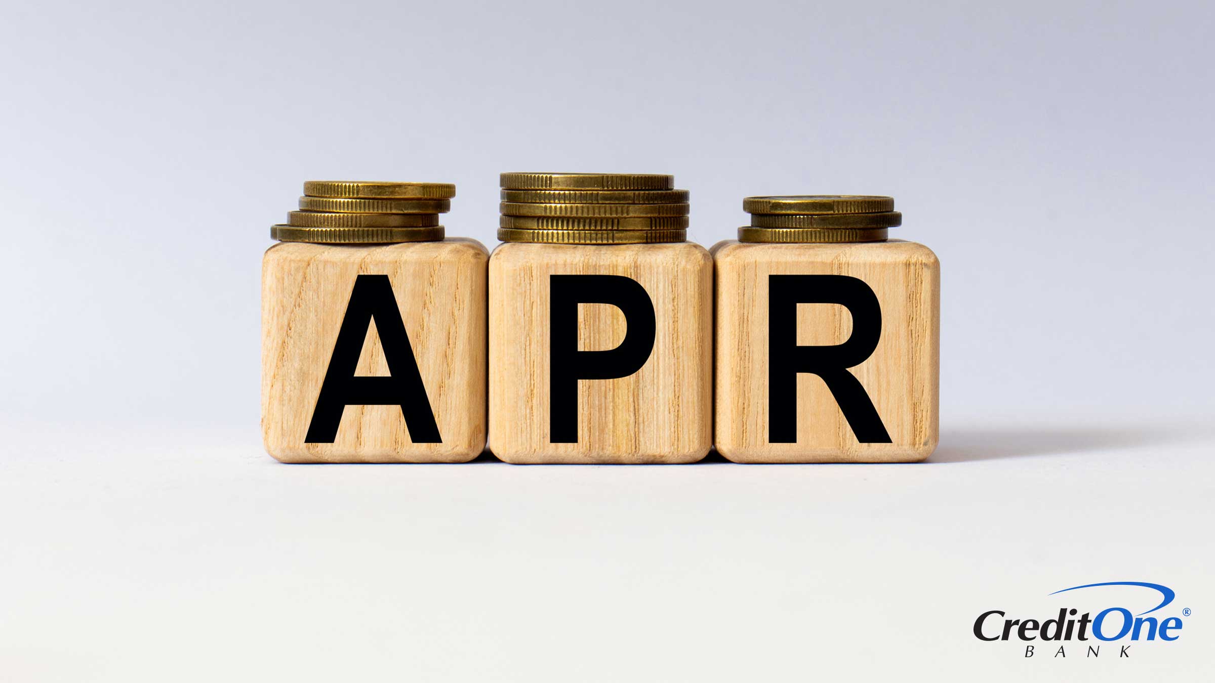 Stacks of coins in various heights sit on top of three wooden blocks spelling out APR, which represents how a credit card APR may get higher based on various criteria.